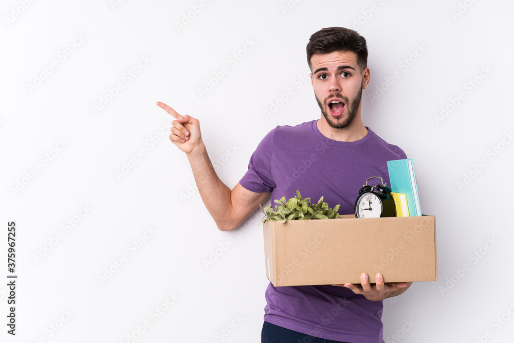 Young caucasian man moving a new home isolated pointing to the side Young caucasian man moving a new home isolated pointing to the side