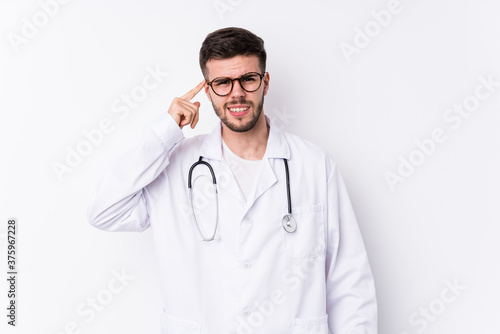Young caucasian doctor man isolated showing a disappointment gesture with forefinger.