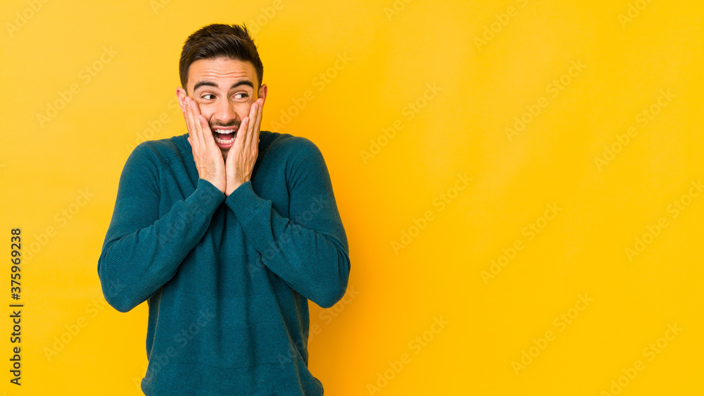 Young caucasian man isolated on yellow bakground scared and afraid.