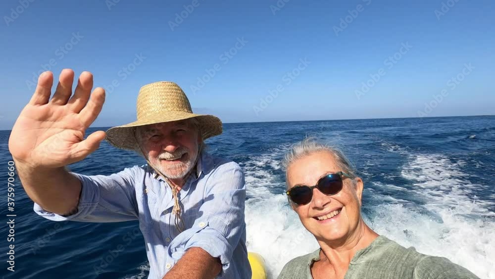 couple of cute mature people or senior enjoying and having fun together in the middle of the sea or ocean with a small boat or dinghy - woman pensioner taking a selfie with her old man driving the boa couple of cute mature people or senior enjoying and having fun together in the middle of the sea or ocean with a small boat or dinghy - woman pensioner taking a selfie with her old man driving the boa