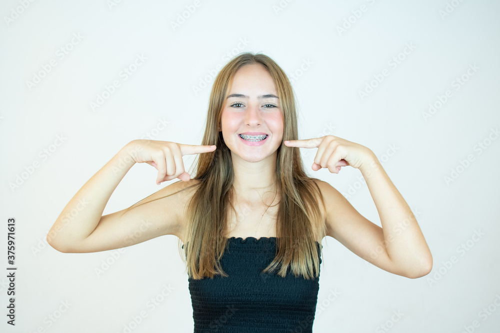 Smiling girl in black top pointing to her teeth Smiling girl in black top pointing to her teeth