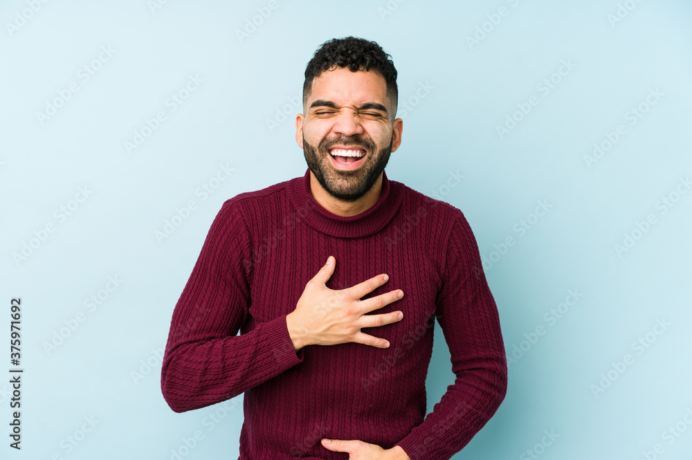 Young mixed race arabic man isolated laughs happily and has fun keeping hands on stomach. Young mixed race arabic man isolated laughs happily and has fun keeping hands on stomach.