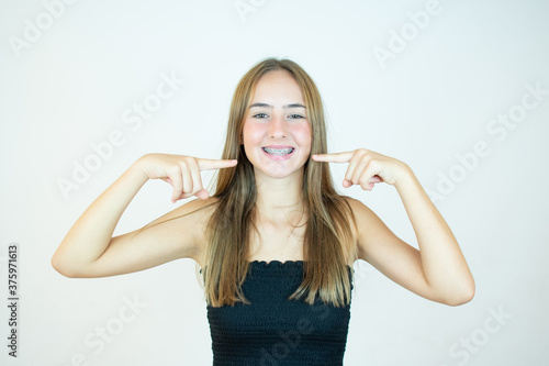 Smiling girl in black top pointing to her teeth