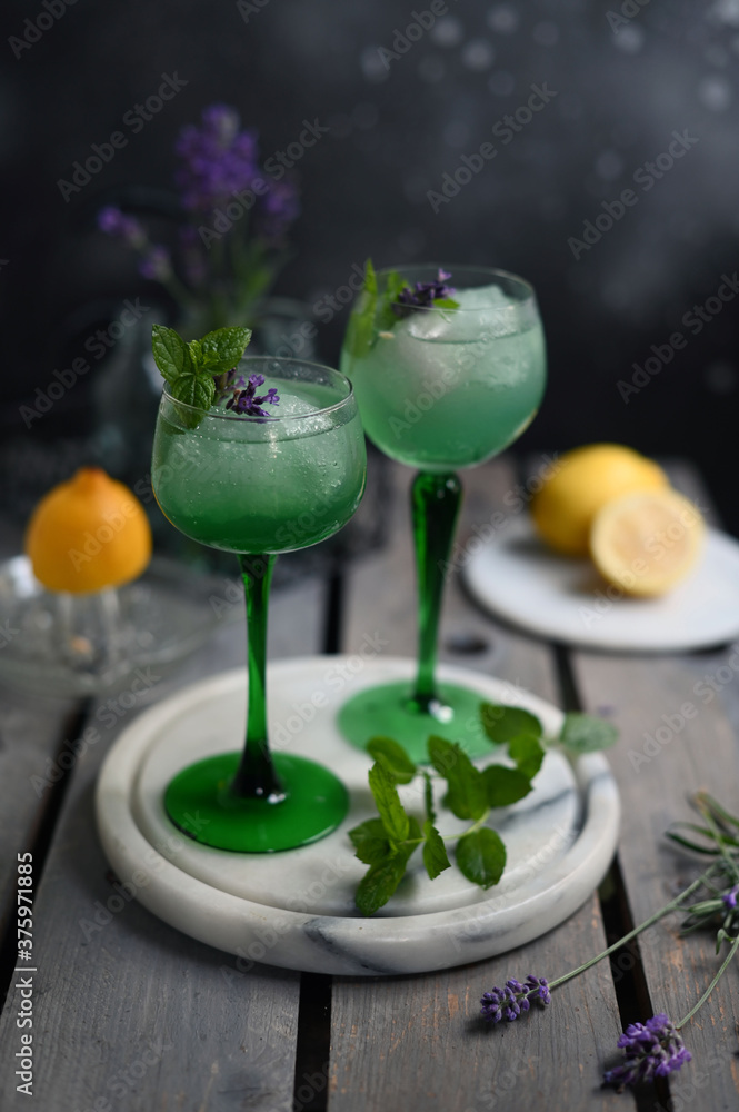 Sparkling Woodruff Drink in a glass . green woodruff drink with ice cubes on black background.