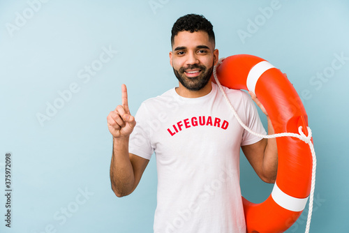 Young latin lifeguard man isolated showing number one with finger.
