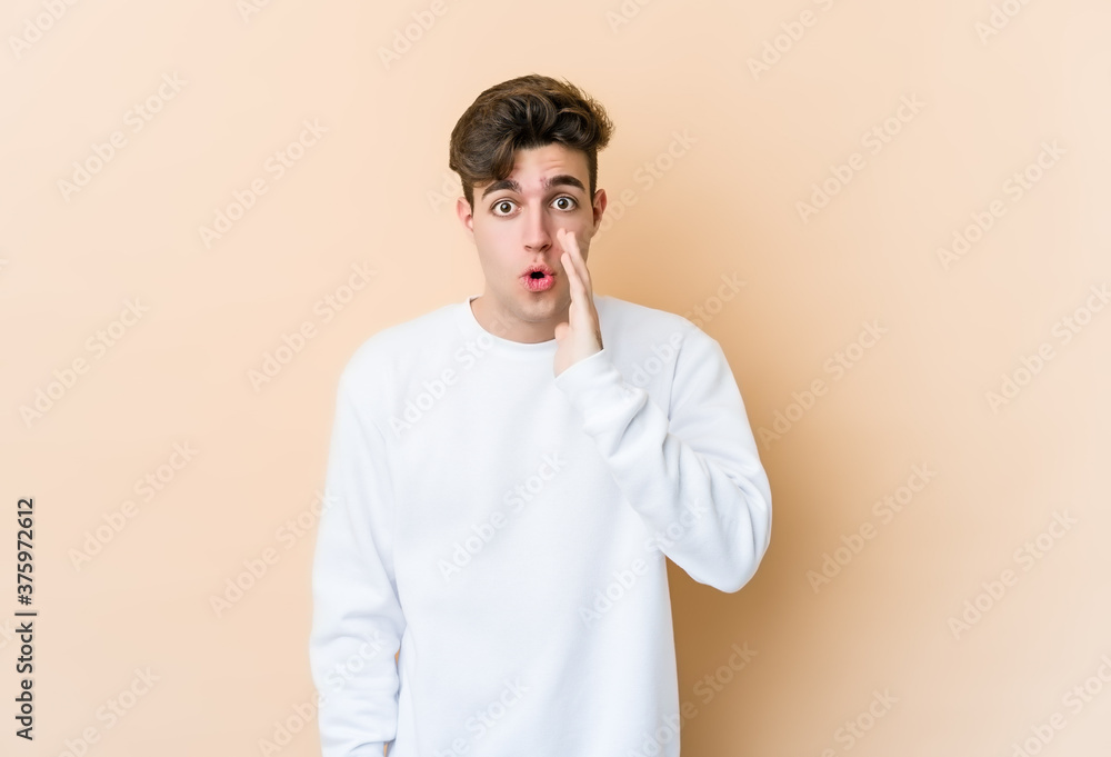 Young caucasian man isolated on beige background is saying a secret hot braking news and looking aside Young caucasian man isolated on beige background is saying a secret hot braking news and looking aside