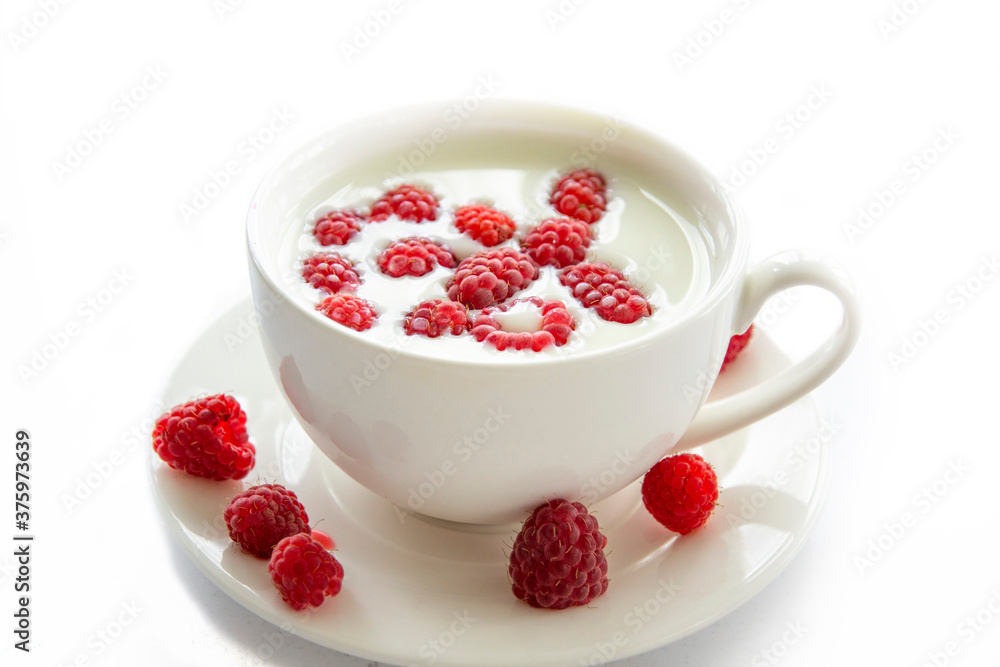 white mug with milk and raspberries in milk on a white background. white mug with milk and raspberries in milk on a white background.