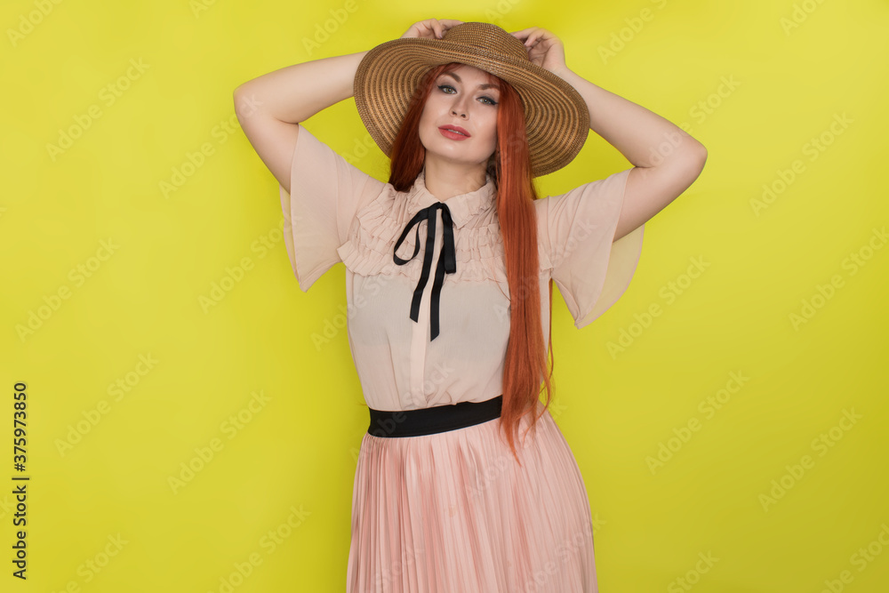 Red haired woman in straw hat over yellow background Red haired woman in straw hat over yellow background