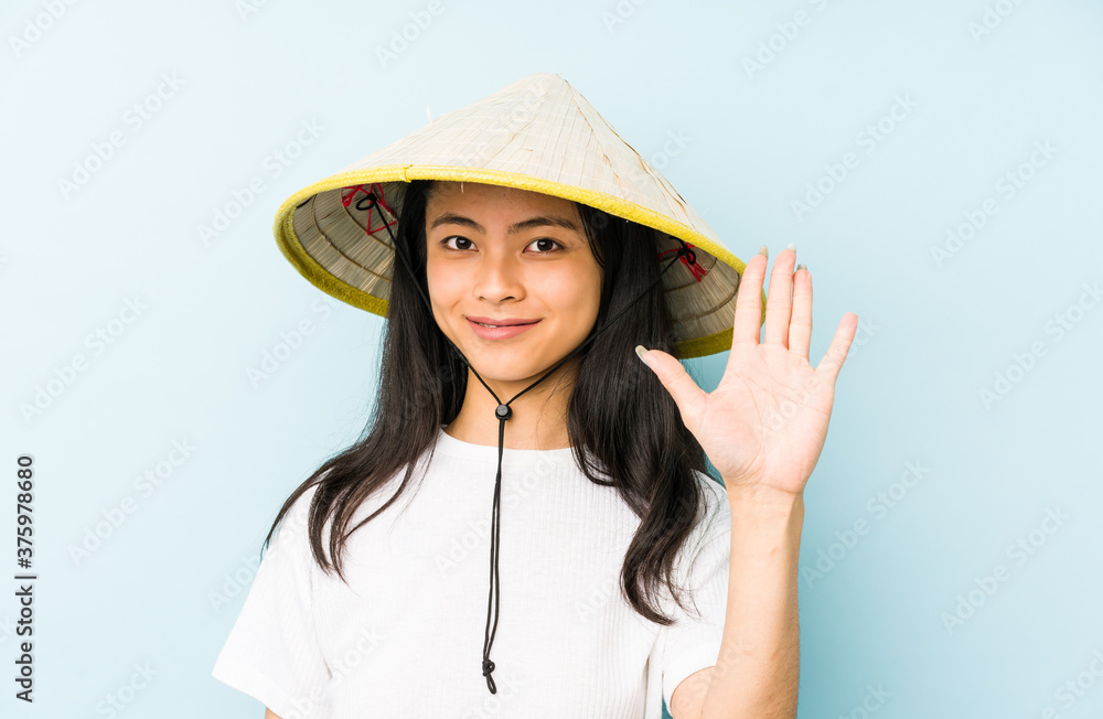 Young chinese woman wearing a vietnamese hay isolated showing a mobile phone call gesture with fingers. Young chinese woman wearing a vietnamese hay isolated showing a mobile phone call gesture with fingers.