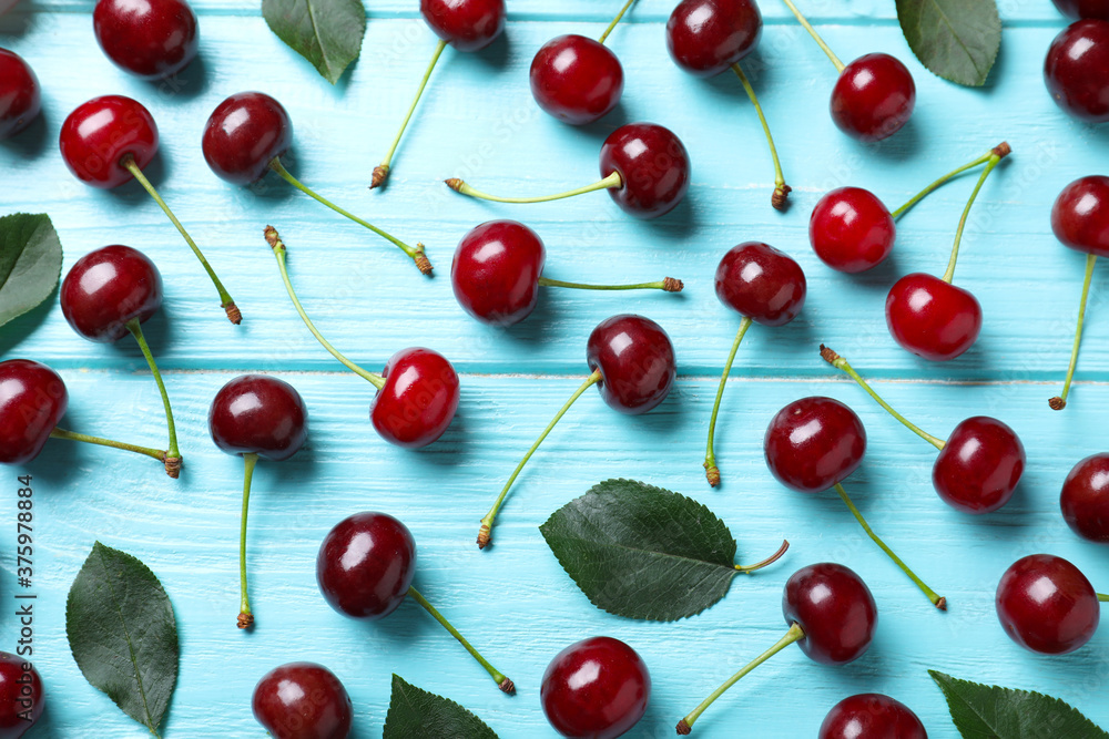 Fototapeta premium Sweet juicy cherries on light blue wooden table, flat lay