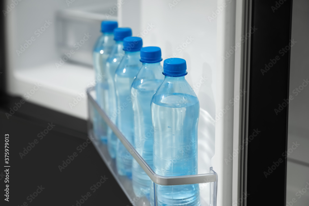 Many bottles with fresh water in fridge door bin, closeup Many bottles with fresh water in fridge door bin, closeup