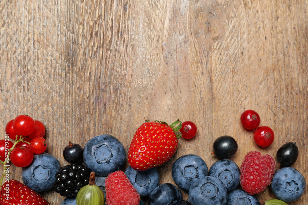 Different fresh berries on wooden table, flat lay. Space for text Different fresh berries on wooden table, flat lay. Space for text