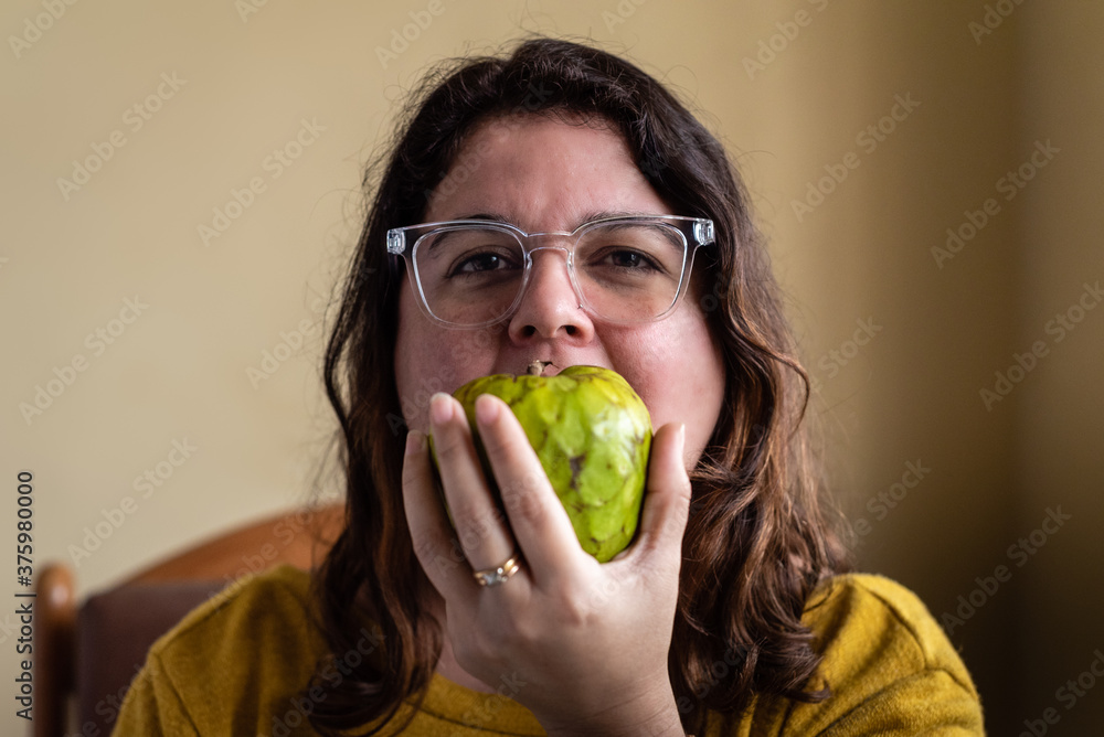 Retrato de una chica mordiendo una chirimoya en casa. Retrato de una chica mordiendo una chirimoya en casa.