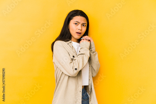 Young chinese woman isolated on a yellow background scared and afraid. © Asier