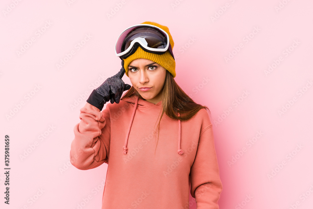 Young caucasian woman wearing a ski clothes isolated pointing temple with finger, thinking, focused on a task. Young caucasian woman wearing a ski clothes isolated pointing temple with finger, thinking, focused on a task.