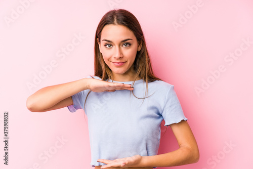 Young caucasian woman wearing a ski clothes isolated holding something with both hands, product presentation.