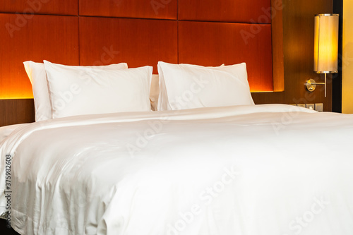 White pillow and blanket on bed with light lamp decoration interior