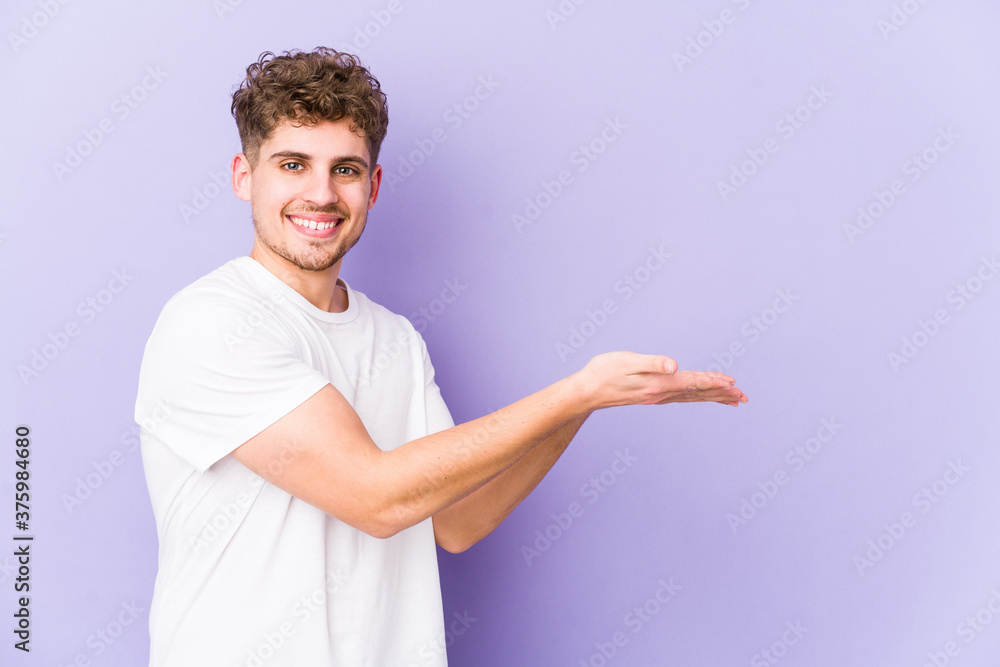 Young blond curly hair caucasian man isolated holding a copy space on a palm. Young blond curly hair caucasian man isolated holding a copy space on a palm.