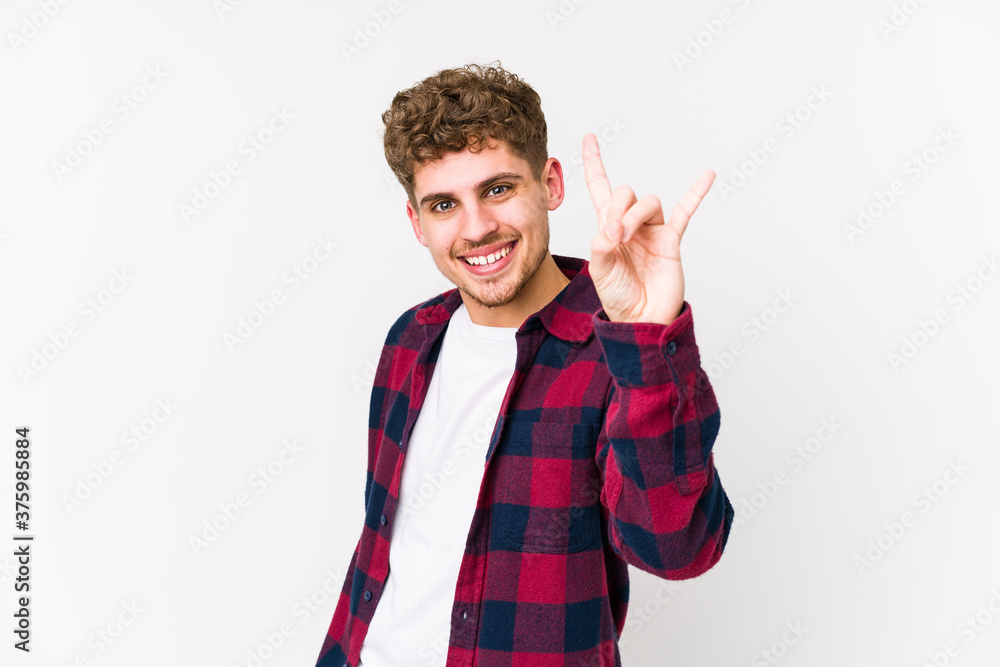 Young blond curly hair caucasian man isolated showing a horns gesture as a revolution concept. Young blond curly hair caucasian man isolated showing a horns gesture as a revolution concept.