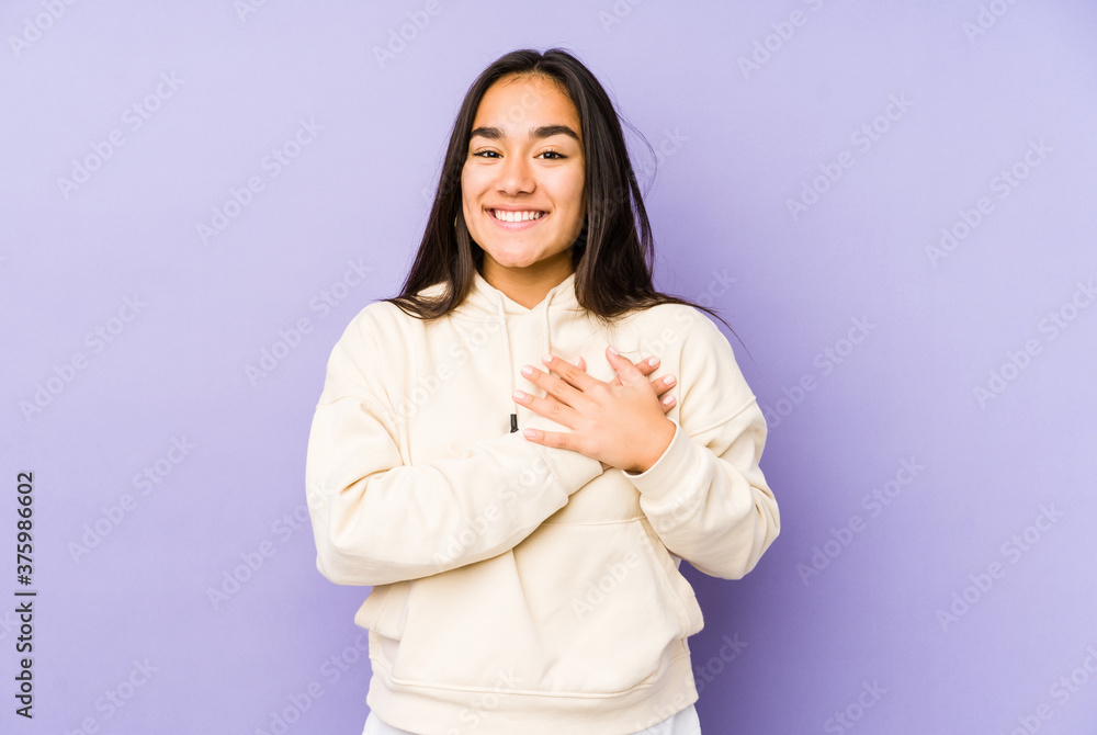 Young woman isolated on a purple background has friendly expression, pressing palm to chest. Love concept. Young woman isolated on a purple background has friendly expression, pressing palm to chest. Love concept.