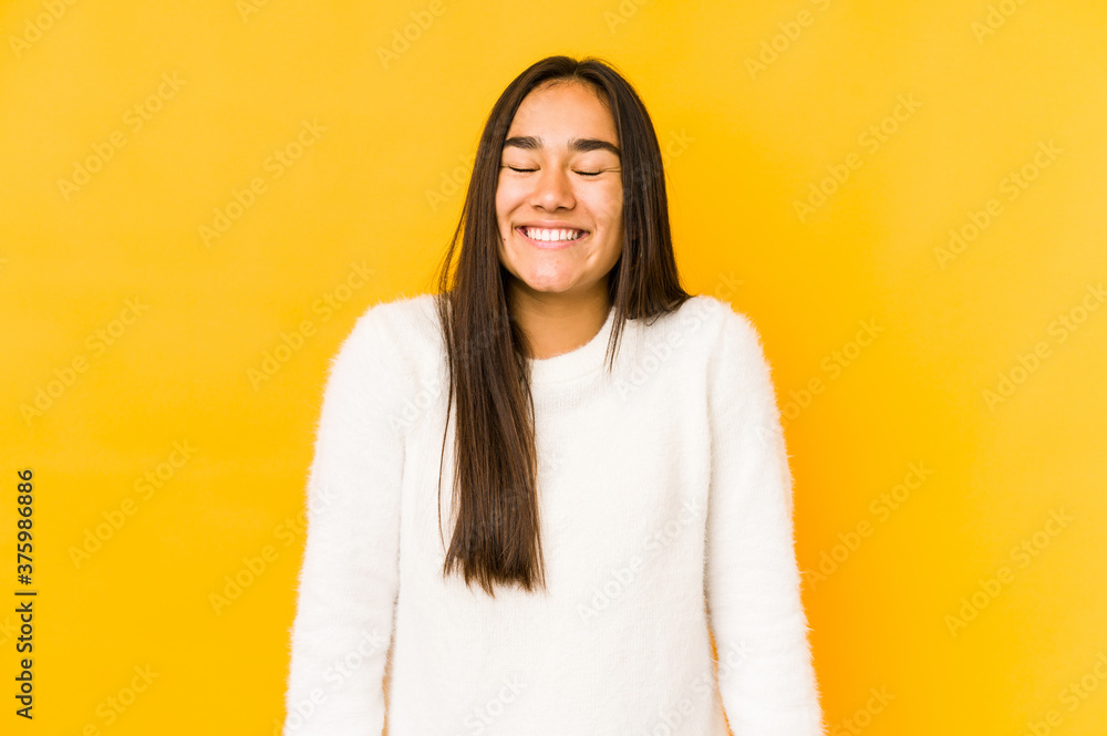 Young woman isolated on a yellow background laughs and closes eyes, feels relaxed and happy. Young woman isolated on a yellow background laughs and closes eyes, feels relaxed and happy.