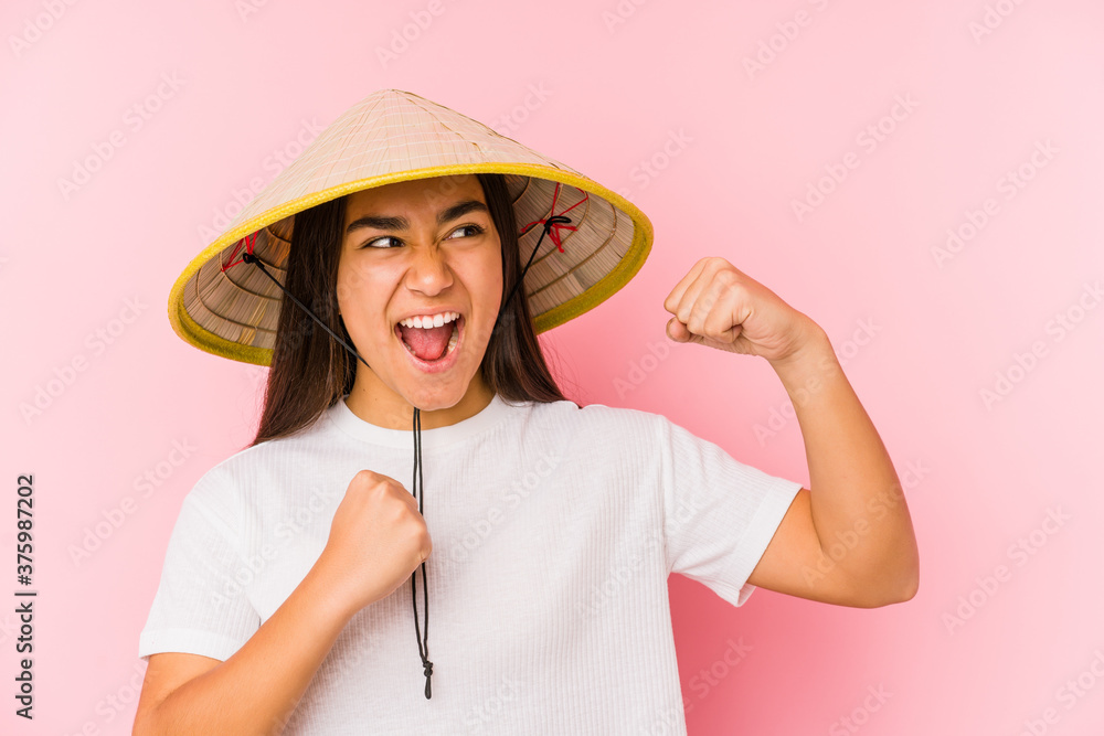 Young asian woman wearing a vietnamese hat isolated Young asian woman wearing a vietnamin hatraising fist after a victory, winner concept. Young asian woman wearing a vietnamese hat isolated Young asian woman wearing a vietnamin hatraising fist after a victory, winner concept.