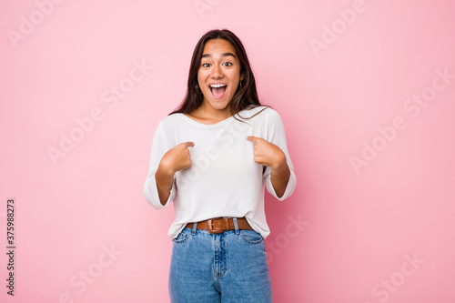 Young mixed race indian woman surprised pointing with finger, smiling broadly. © Asier