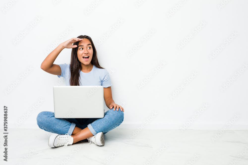 Young mixed race indian woman sitting working on laptop looking far away keeping hand on forehead. Young mixed race indian woman sitting working on laptop looking far away keeping hand on forehead.