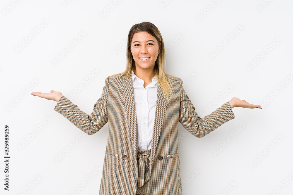 Young caucasian business woman isolated makes scale with arms, feels happy and confident. Young caucasian business woman isolated makes scale with arms, feels happy and confident.