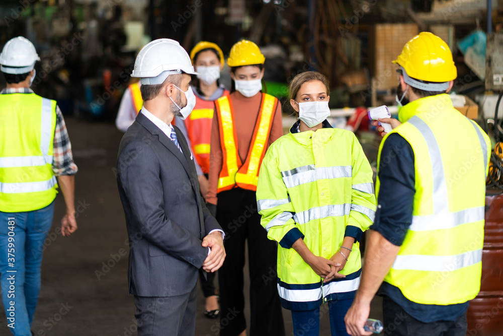 Temperature measurement with employee temperature meter before entering work at factory. Professional engineering team. Temperature measurement with employee temperature meter before entering work at factory. Professional engineering team.