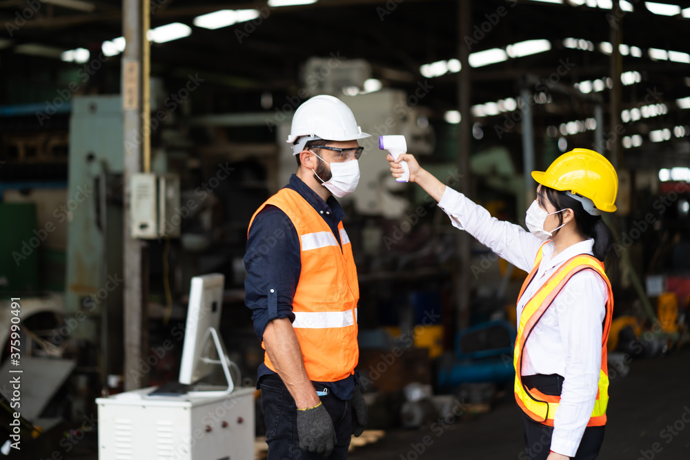 Temperature measurement with employee temperature meter before entering work at factory. Professional engineering team. Temperature measurement with employee temperature meter before entering work at factory. Professional engineering team.