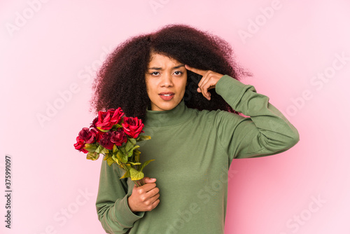 Young afro woman holding a roses isolated Young afro woman holding a rosesshowing a disappointment gesture with forefinger.