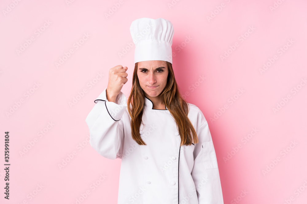 Young caucasian chef woman isolated showing fist to camera, aggressive facial expression. Young caucasian chef woman isolated showing fist to camera, aggressive facial expression.