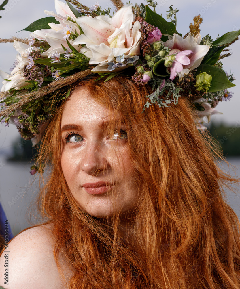Naklejka premium Slavic beauty with a flower wreath on her head in the lap of nature. Ancient pagan origin celebration concept. Summer solstice day. Mid summer. Ancient rituals.