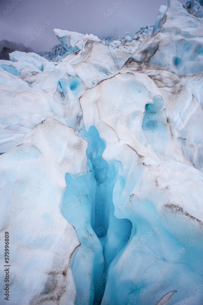 Fototapeta premium Close view of the blue glaciers in Vatnajokull National Park, in Iceland, on a cloudy day.