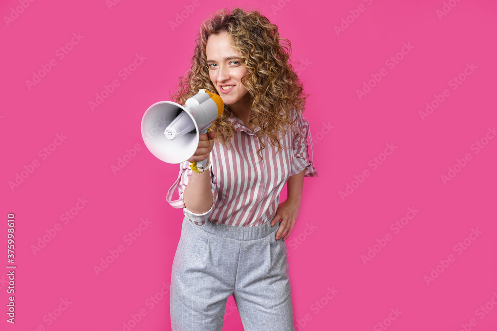 Young woman speaks into a megaphone. Isolated pink background. Young woman speaks into a megaphone. Isolated pink background.