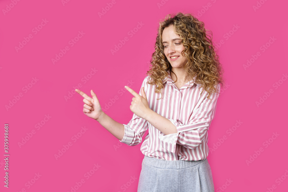A cheerful woman points to a copy space, discusses an amazing ad, gives way or a direction, wears a striped shirt, has a pleasant smile, and feels optimistic A cheerful woman points to a copy space, discusses an amazing ad, gives way or a direction, wears a striped shirt, has a pleasant smile, and feels optimistic