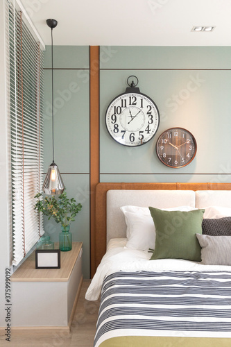Modern green and brown bedroom with striped pattern. large wall clock on wall.