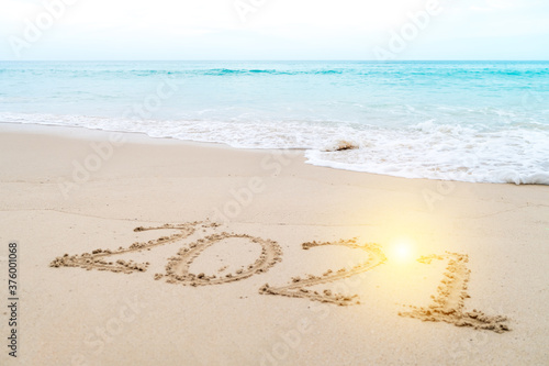 2021 year hand drawn on sand summer beach.