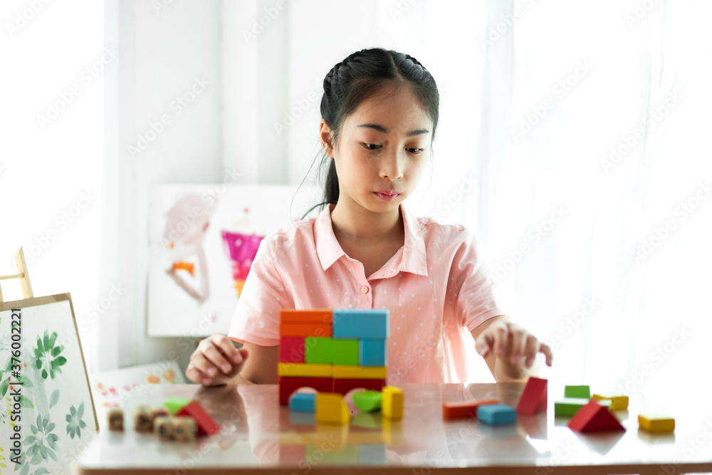 Little cute girl enjoy while playing wooden blocks toys on table at home Little cute girl enjoy while playing wooden blocks toys on table at home