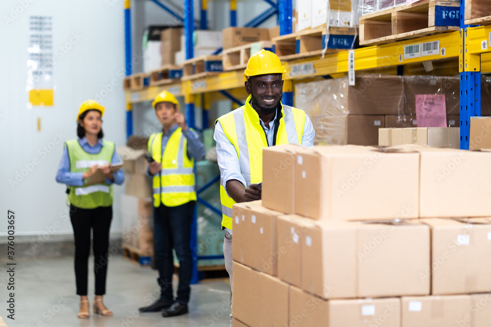 Black Male warehouse worker pulling a pallet truck. middle aged African American warehouse worker preparing a shipment in large warehouse distribution centre Black Male warehouse worker pulling a pallet truck. middle aged African American warehouse worker preparing a shipment in large warehouse distribution centre
