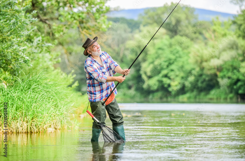 Fishing is fun. mature man fly fishing. man catching fish. summer weekend. Big game fishing. retired bearded fisher. Trout bait. fisherman with fishing rod. hobby and sport activity. pothunter Fishing is fun. mature man fly fishing. man catching fish. summer weekend. Big game fishing. retired bearded fisher. Trout bait. fisherman with fishing rod. hobby and sport activity. pothunter