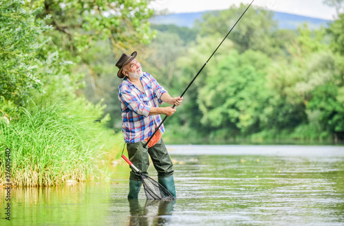 Fishing is fun. mature man fly fishing. man catching fish. summer weekend. Big game fishing. retired bearded fisher. Trout bait. fisherman with fishing rod. hobby and sport activity. pothunter