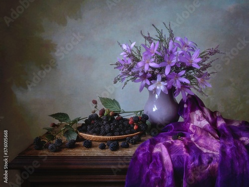 Still life with bouquet of purple flowers and blackberries