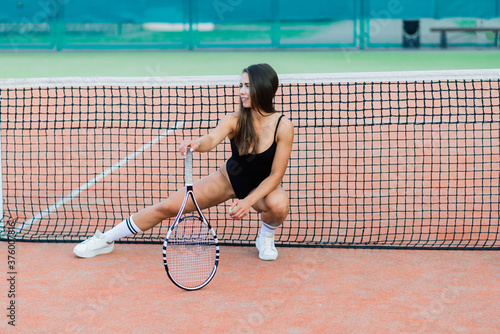 Beautiful young free sports sexy fitness girl dressed in bodysuit on a sports ground on tennis court