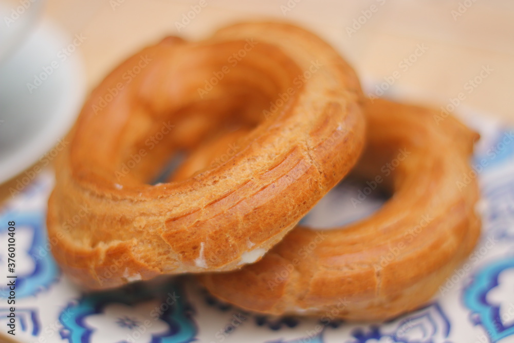 Morning. Espresso coffee in a porcelain cup on a saucer. Cake Ring with cream on a square plate with oriental ornaments Morning. Espresso coffee in a porcelain cup on a saucer. Cake Ring with cream on a square plate with oriental ornaments