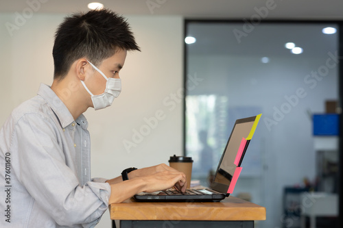 Business man working job on labtop and wering mask in office.