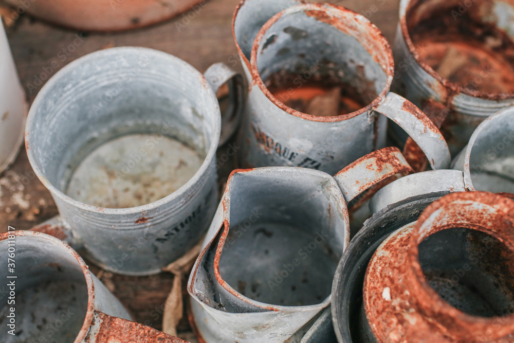 Old rustic metal silver pot and and brown-orange clay pot on a black wooden table outdoor in garden to decorate the house or decorate the green terrace. Old rustic metal silver pot and and brown-orange clay pot on a black wooden table outdoor in garden to decorate the house or decorate the green terrace.