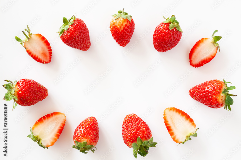 Oval frame of whole and halved strawberries on white background. Isolated. Copy space. Oval frame of whole and halved strawberries on white background. Isolated. Copy space.