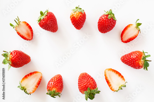 Oval frame of whole and halved strawberries on white background. Isolated. Copy space.